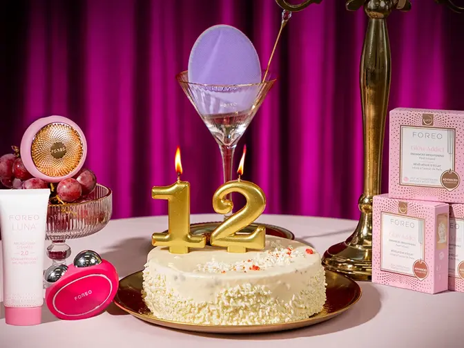 FOREO devices and cosmetics around a birthday cake with the candles showing the number 12
