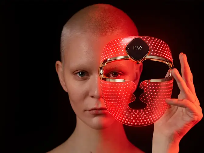 A woman taking off her FAQ 202 red light face mask