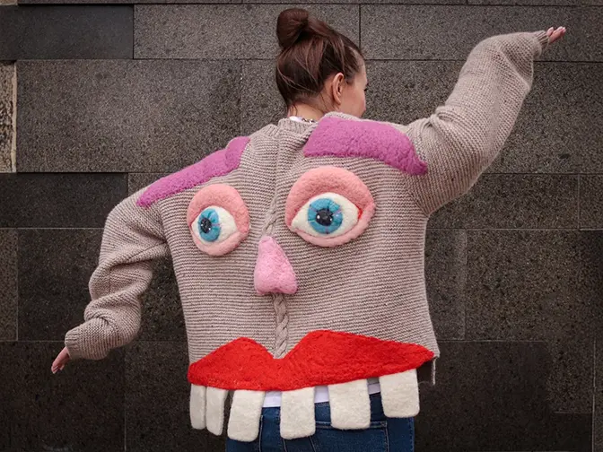 A woman dancing in a knitted jacket with face and teeth