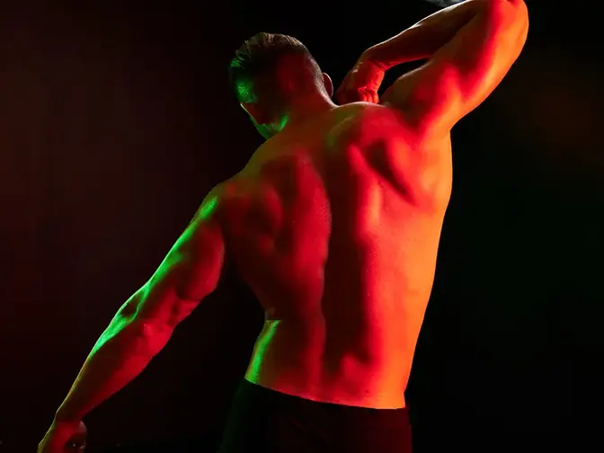 A muscular man's back in red light