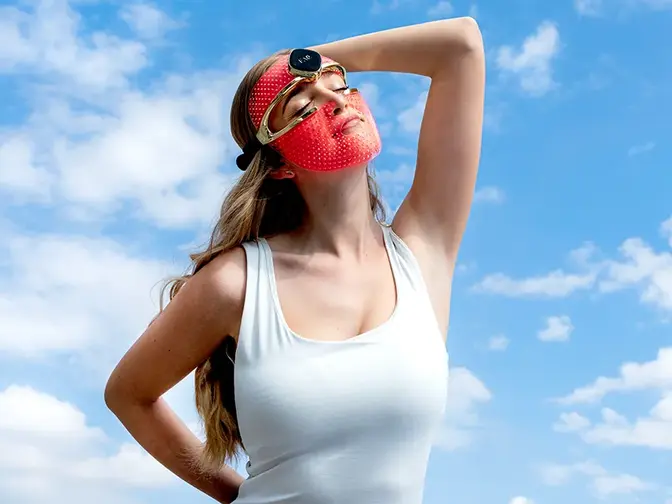 A young woman in a white top wearing FAQ 202 red LED light mask