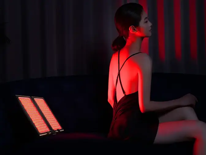 A woman in a gorgeous black spagetti strap nightie criss-crossed at the back having red light therapy 