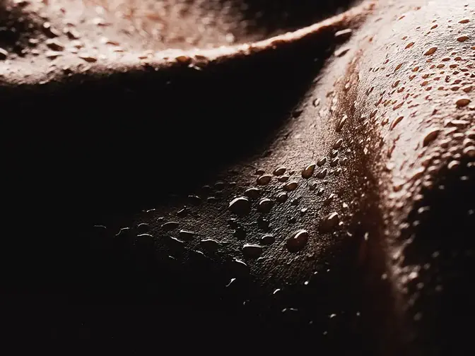 A closeup of dark skin with bads of sweat on it