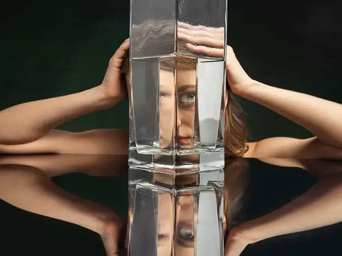 A woman on a black backgorund looking through a huge jug of water defoirming her features