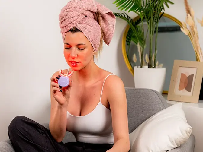 A young woman with a towel on her hair using issa TEETH WHITENING SET