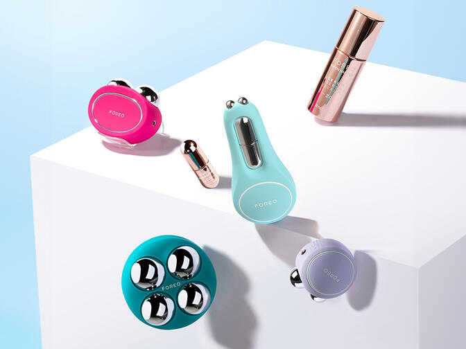 FOREO BEAR 2, BEAR 2 body, BEAR 2 go, BEAR eyes&lips, SUPERCHARGED Serum, SUPERCHARGED Eye & Lip Contour Booster floating over a white cube on a light blue background