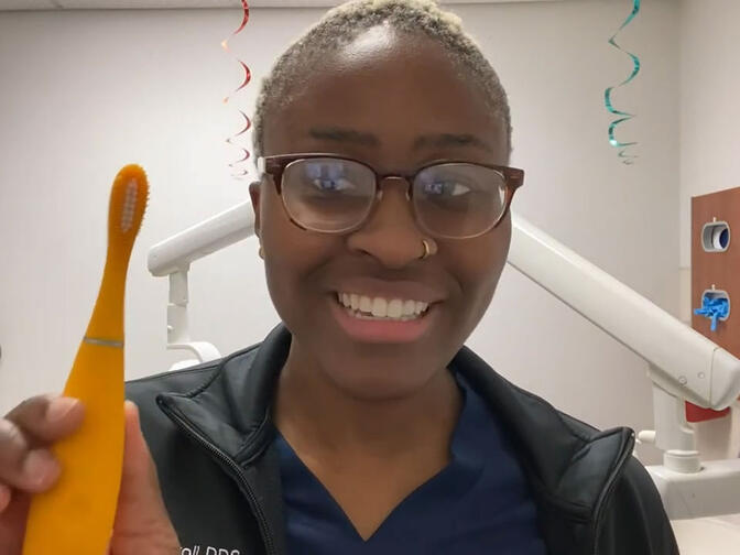 A dentist sitting at her office holding FOREO ISSA kids toothbrush