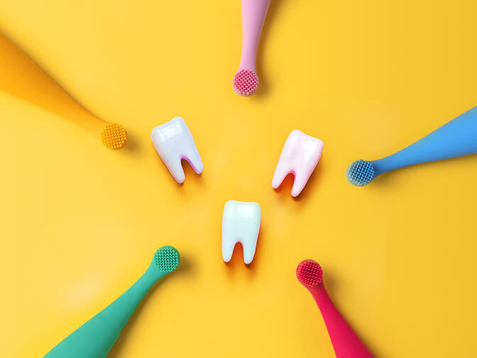 Five FOREO ISSA baby toothbrushes in various colors with three teeth in the middle
