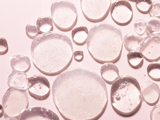 Transparent drops of various sizes on a pink background