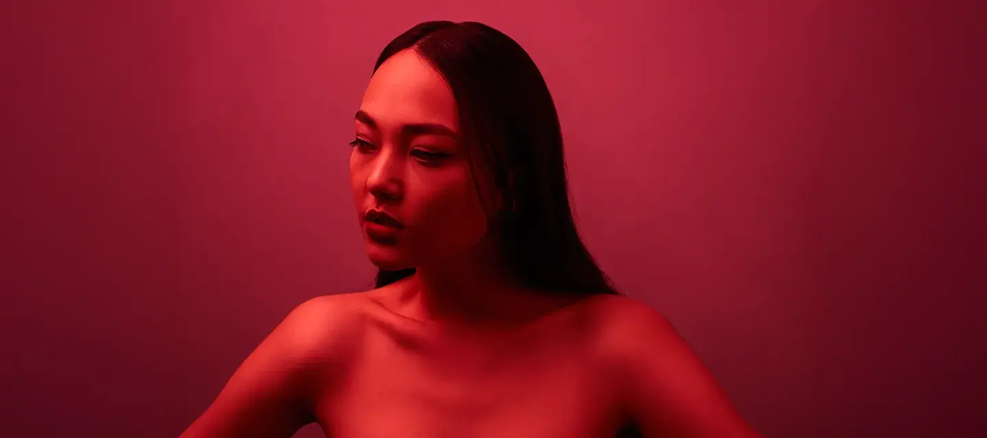 red light therapy wavelength A gorgeous Asian descent woman in a glowing red light