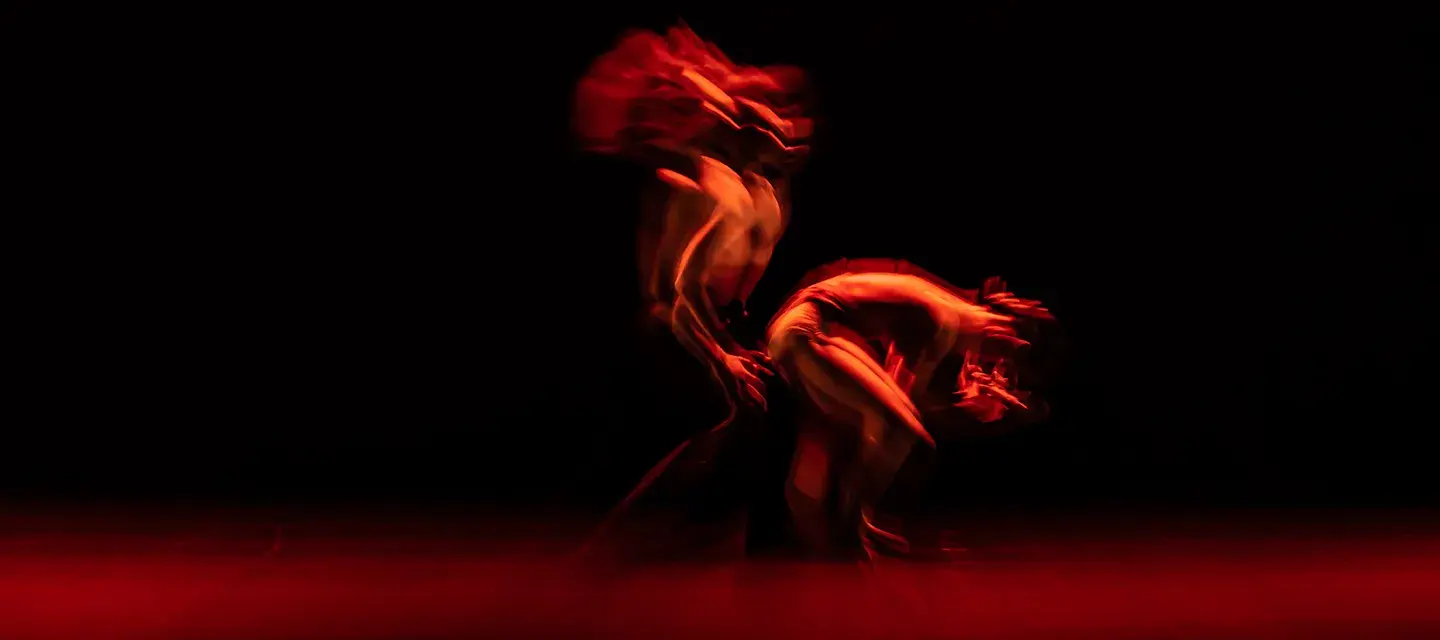 An abstract dance in a dark room with red lights representing the dualism and similarities of red light therapy vs infrared