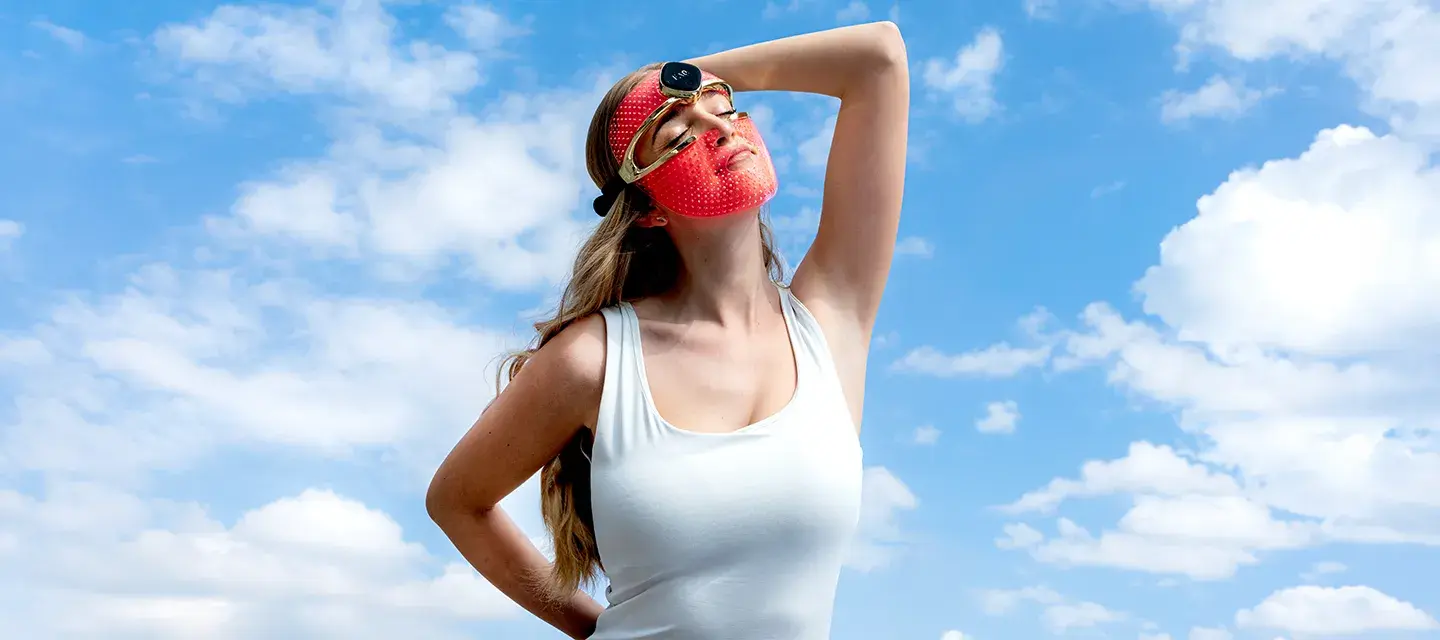 A young woman in a white top wearing FAQ 202 red LED light mask
