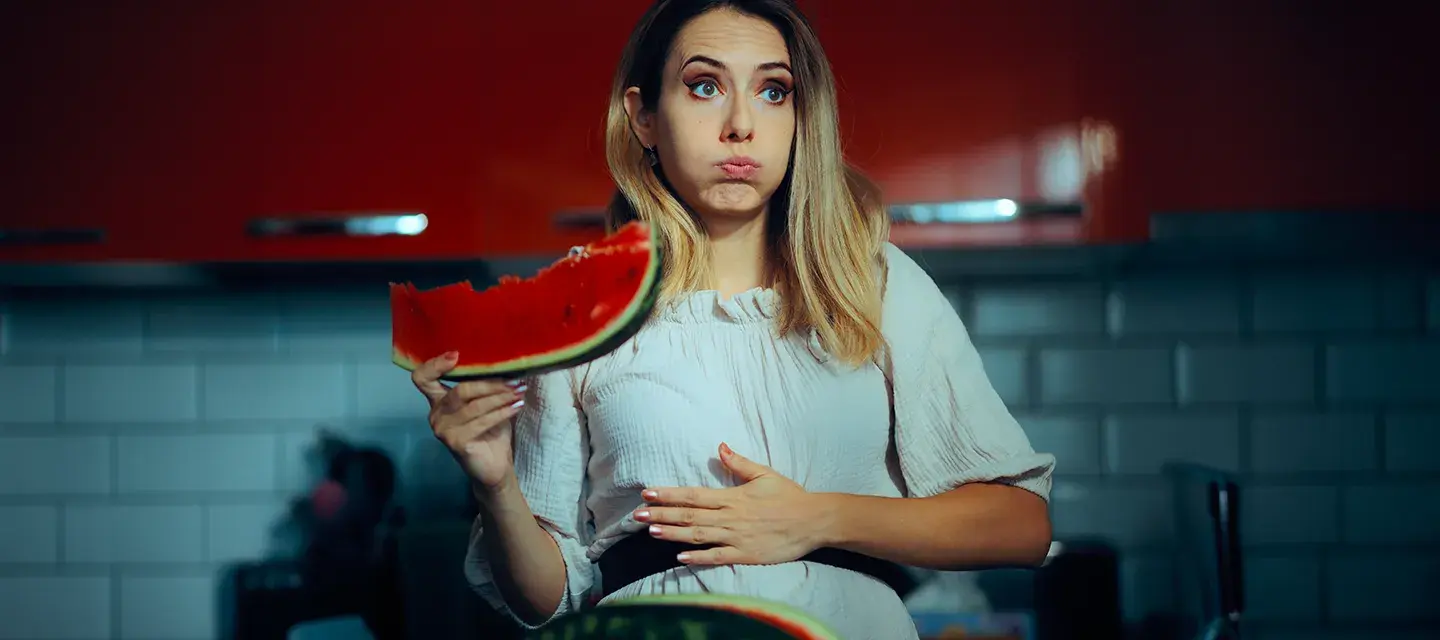 A bloated woman eating a watermellon  