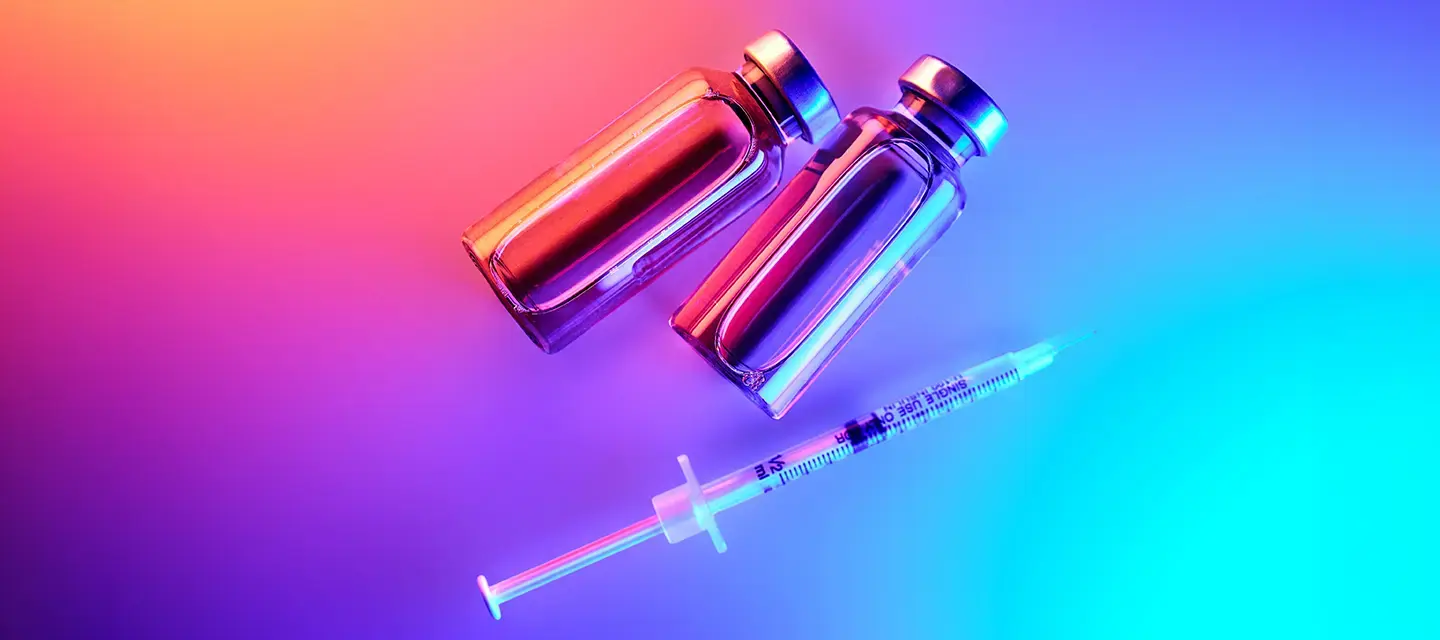 GLP-1 bottles and a syringe under neon lights