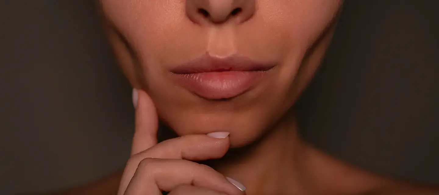 A woman with sunken cheeks wandering how to avoid Ozempic face on a dark background