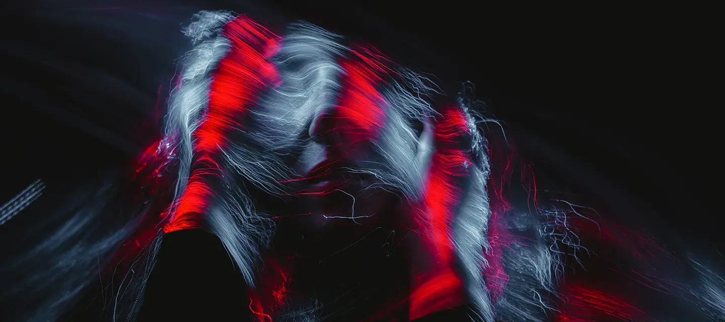 An abstract photo of a woman in the dark with red light over her hair