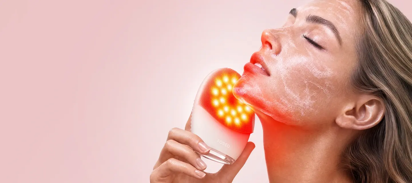 A woman using LUNA 5 LED face cleansing brush