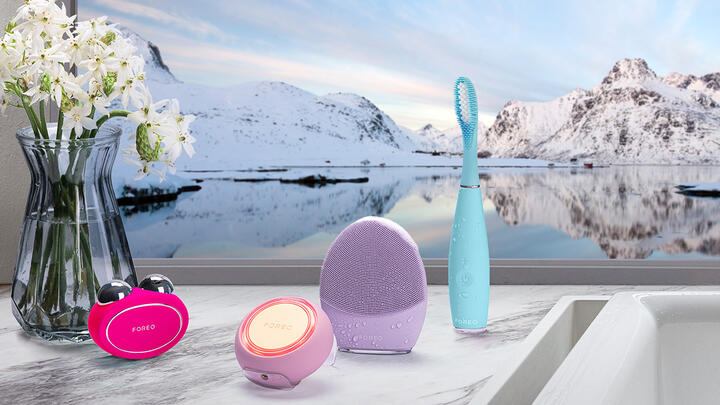 FOREO devices left to right; BEAR 2, UFO 3, LUNA 4, ISSA 3 in a bathroom, snowy mountains in the background