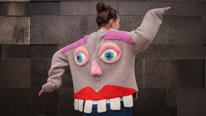 A woman dancing in a knitted jacket with face and teeth