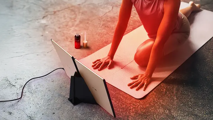 Woman doing yoga in fron of FAQ DUAL LED PANEL red light therapy at home device