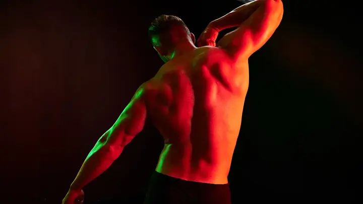 A muscular man's back in red light