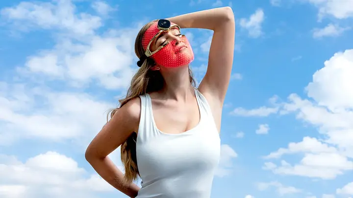 A young woman in a white top wearing FAQ 202 red LED light mask