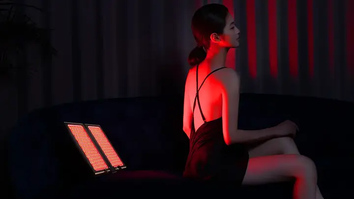 A woman in a gorgeous black spagetti strap nightie criss-crossed at the back having red light therapy 