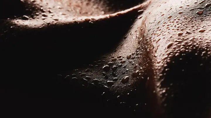 A closeup of dark skin with bads of sweat on it