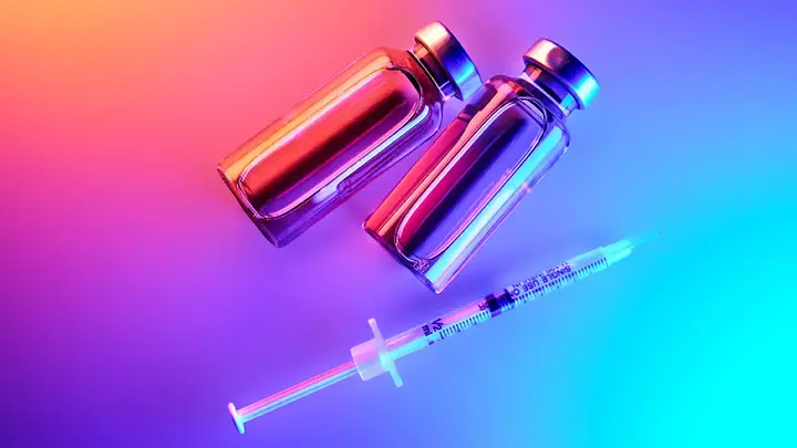 GLP-1 bottles and a syringe under neon lights