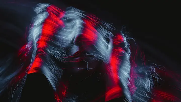 An abstract photo of a woman in the dark with red light over her hair