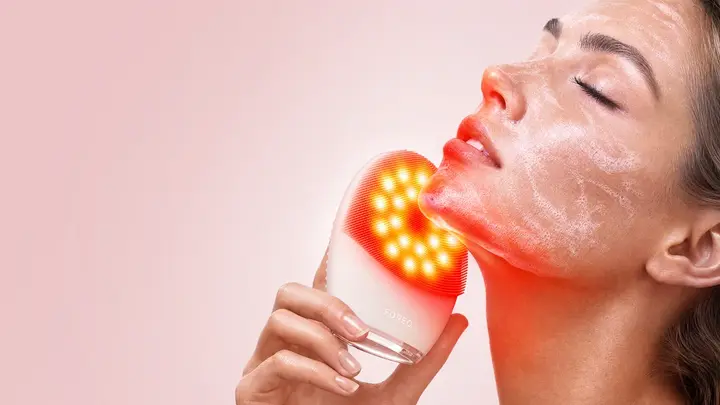 A woman using LUNA 5 LED face cleansing brush