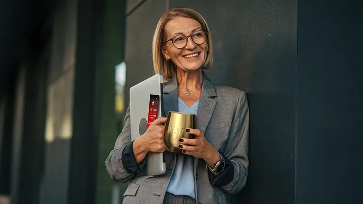A mature vital business woman drinking vitamins for womens health from a golden cup