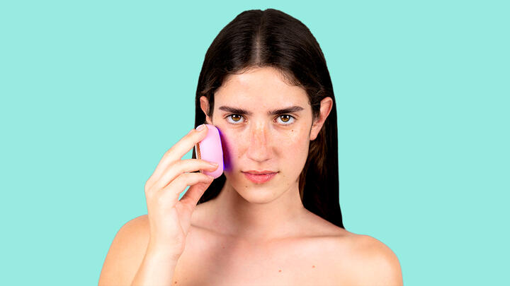 UFO 3 hydration device increases skin moisture by 126% in under 2 minutes of treatment. A closeup of a young woman holding FOREO UFO 3 deep hydration device in pearl pink color pressed to her cheek. She stands in front of a turquoise background.